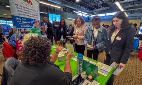  A group of female students talk with representatives from Smart Start 